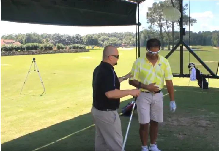 Adrian Quevedo works with Michael Campbell on the driving range under a canopy