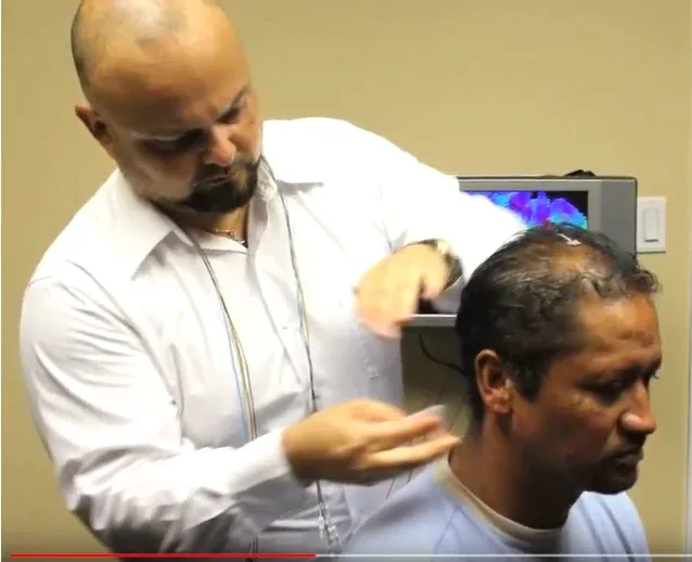 Adrian Quevedo places neurofeedback sensors on golfer Michael Campbell’s scalp before a training session, with his brain map on the screen behind them
